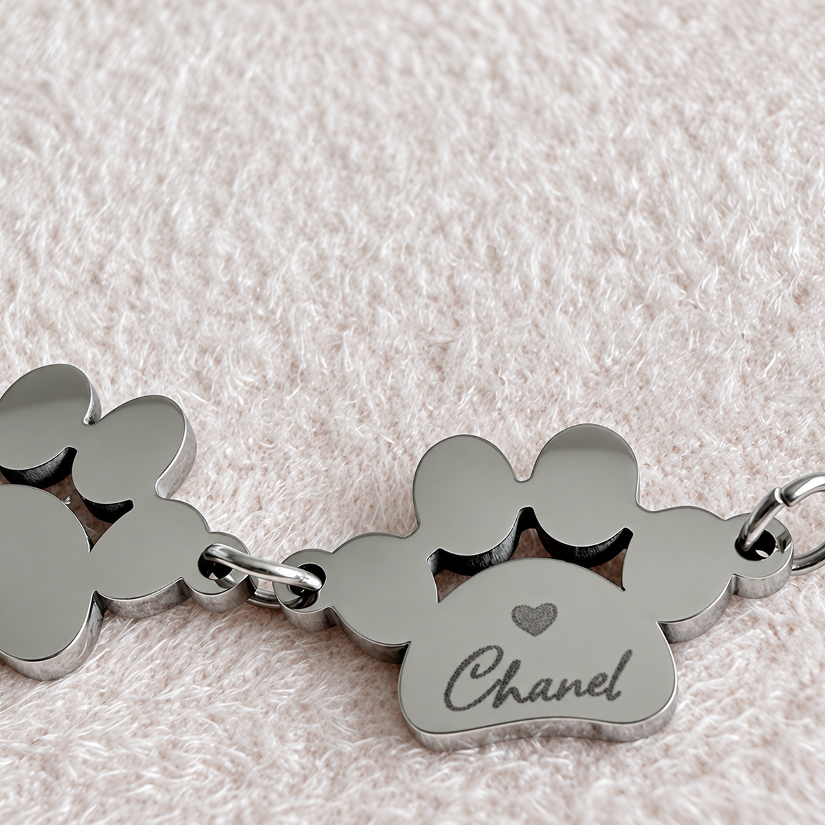 Primo piano del braccialetto personalizzato con due ciondoli a forma di zampa incisi con il nome del cane o del gatto CG CREAZIONS Svizzera